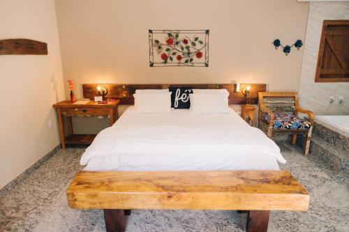 a bedroom with a white bed with a wooden table at Pousada Adega Cipo in Serra do Cipo