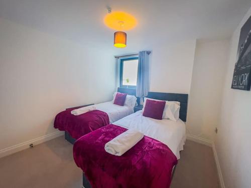 two beds in a room with purple and white sheets at 30% Off Monthly Stay/2Bed House - Sittingbourne in Kent