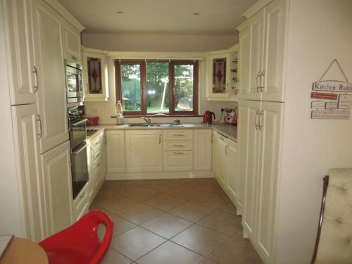una cocina con armarios blancos y una silla roja. en Borodino Studio Apartment en Enniscorthy