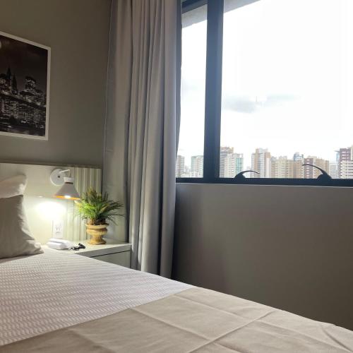 a bedroom with a bed and a large window at THE ONE - Flat Batel Premium in Curitiba