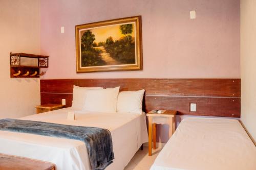 a hotel room with two beds and a picture on the wall at Pousada Adega Cipo in Serra do Cipo