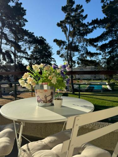 a white table with a vase of flowers on it at Condominio en El Tabo - tranquilidad y seguridad in El Tabo