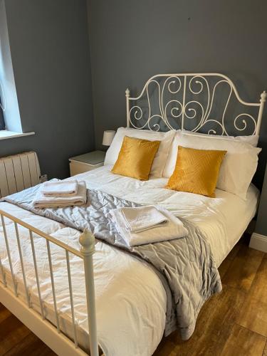 1 dormitorio con 1 cama con sábanas blancas y almohadas de oro en Woodquay Mews en Galway