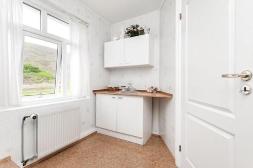 a white kitchen with a sink and a window at Mjoeyri Travel Holiday Homes in Eskifjörður