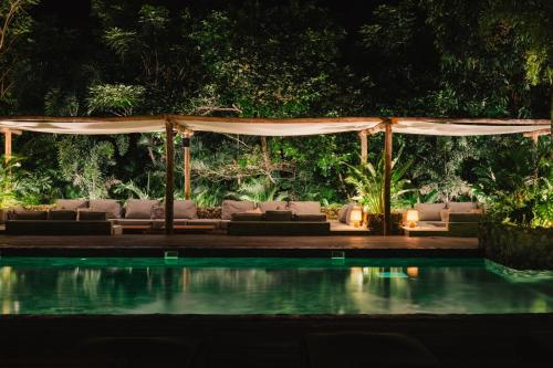 a pavilion with couches and a pool at night at Naio Hotel y Villas By OxoHotel in Palomino