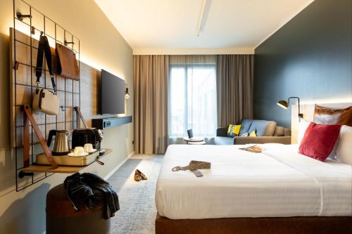a hotel room with a large bed and a couch at Moxy Paris Val d'Europe in Montévrain