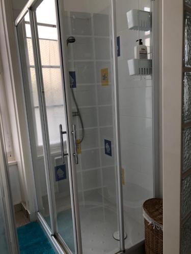 une douche avec une porte vitrée dans une salle de bain dans l'établissement Location cure ou vacances dans maison charentaise centre ville, à Saujon