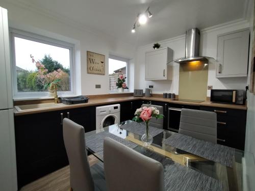 uma cozinha com uma mesa com um vaso de flores em Polaris House - sleeps 6, driveway, garden em Crewe