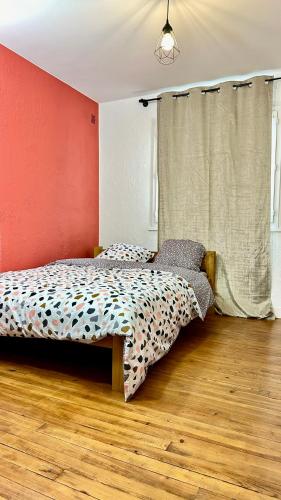 une chambre avec un lit et un mur rouge dans l'établissement LE BORD DE LA LOIRE - chambre avec salle de bains commune, à Nantes