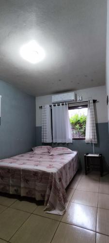 a bedroom with a large bed with a window at uma casa na viagem in Três Cachoeiras