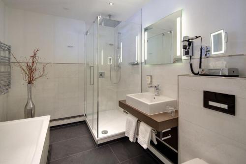 a bathroom with a glass shower and a sink at Hotel Am Markt Nordenham in Nordenham
