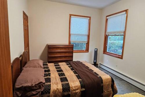a bedroom with a bed and a dresser and two windows at Private Apartment in Catskills in Liberty