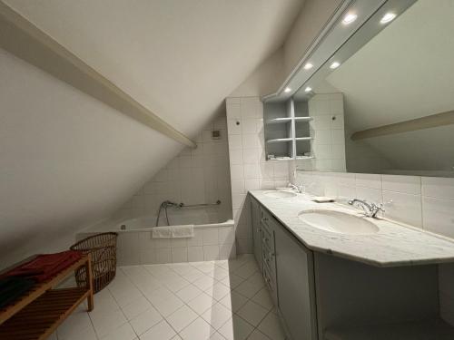 ein weißes Badezimmer mit einem Waschbecken und einer Badewanne in der Unterkunft Duplex Rosières - 12’ de Bruxelles in Rixensart