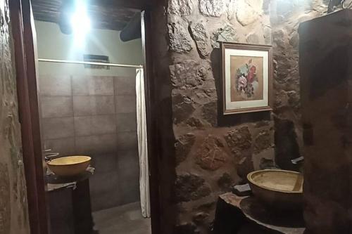 een stenen badkamer met een wastafel en een douche bij finca de barcena, country house in Tumbaya