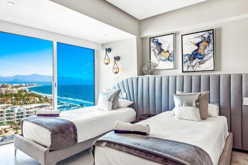twee bedden in een kamer met een groot raam bij Ocean Vista Oasis at Maritima Playa in Bucerías