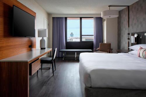 a hotel room with a bed and a desk with a television at New York LaGuardia Airport Marriott in Queens