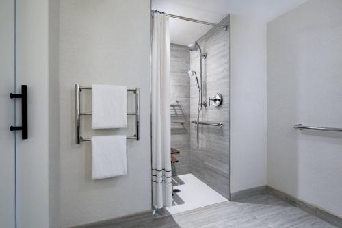 baño con ducha y puerta de cristal en New York LaGuardia Airport Marriott, en Queens