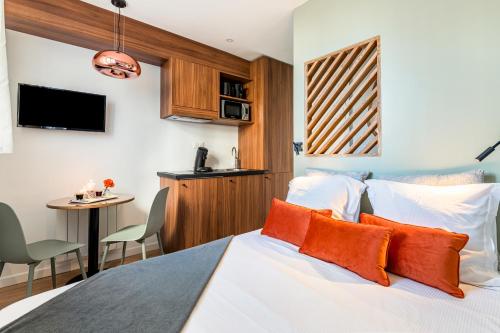 1 dormitorio con cama con almohadas de color naranja y mesa en Studios Part-Dieu Gare - HomaLyon, en Lyon