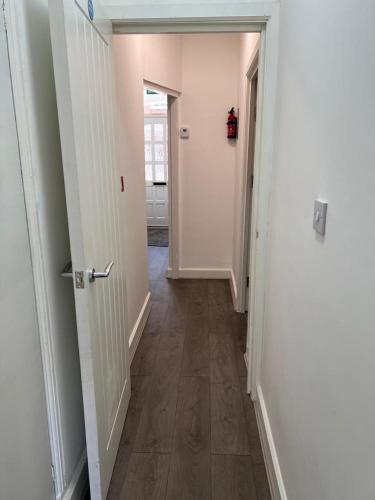 a hallway with an open door to a room with wooden floors at ENSUITE ROOM AT HAYES in Hayes