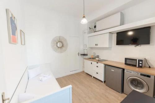 une cuisine blanche avec une machine à laver et un micro-ondes dans l'établissement Cosy studio à Asnières, à Asnières-sur-Seine