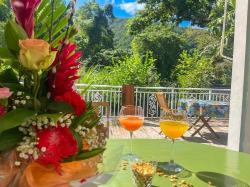 two wine glasses on a table with a vase of flowers at Studio Jo'kmi in Pointe-Noire