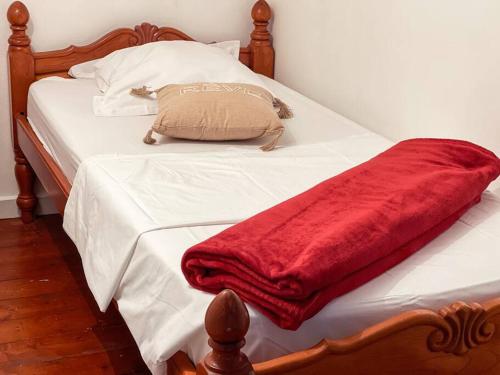 a white bed with a red blanket on it at Studio Jo'kmi in Pointe-Noire