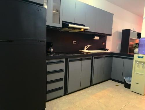 Boca de Aroa的住宿－Tucacas, Sotavento，厨房配有白色橱柜和黑色冰箱。