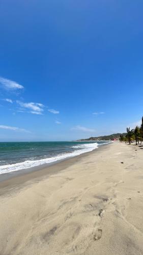 an empty beach with palm trees and the ocean at Hospedaje & Casa Playa AURORA in Zorritos
