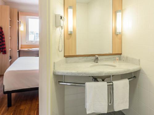 baño con lavabo y cama en ibis Blumenau, en Blumenau