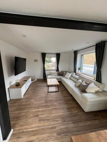 a living room with a white couch and a flat screen tv at Traumfabrik Eifel mit Sauna & Whirlpool in Monschau