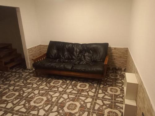a black leather couch in a room with a carpet at La Familia in General Roca
