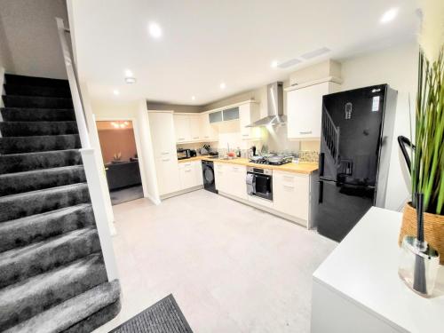 a kitchen with white cabinets and a black refrigerator at Stay Sleep Rest - Heeley in Heeley