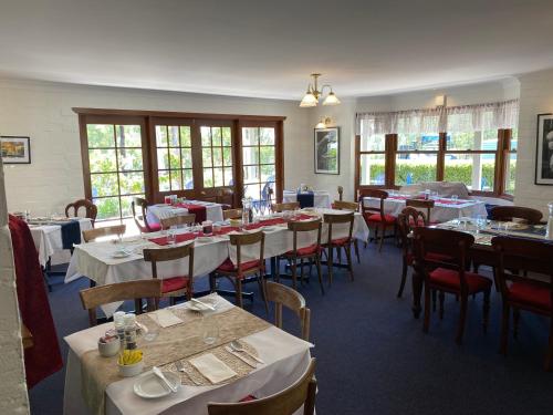 a dining room with white tables and chairs and windows at Girraween Country Inn in Ballandean