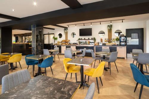 a restaurant with tables and chairs and a bar at Sure Hotel by Best Western Rouvignies Valenciennes in Valenciennes