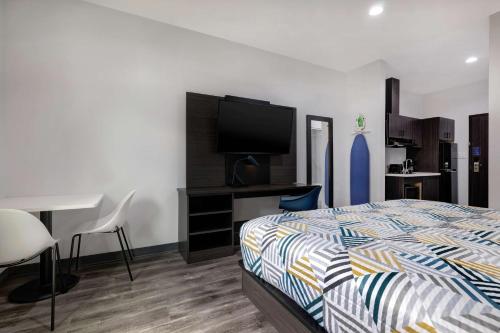 Schlafzimmer mit einem Bett, einem Schreibtisch und einem Flachbild-TV in der Unterkunft Studio 6 Katy, TX Energy Corridor in Katy