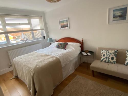 een slaapkamer met een bed, een stoel en een raam bij Bright Suite in Whitstable