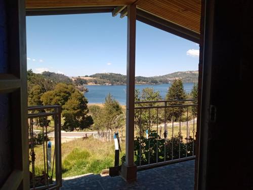 a person standing on a balcony looking out at a lake at Finca Refugio Guanumen in Tota