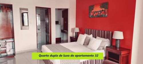 ein Schlafzimmer mit einem Bett mit einer roten Wand in der Unterkunft Príncipe de Mónaco Boutique House in Angra do Heroísmo
