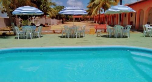 einen Pool mit Stühlen und Sonnenschirmen am Strand in der Unterkunft Pousada Praia Dos Coqueiros in Conde