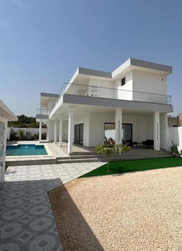 a large white house with a swimming pool at Villa Nohady : luxe, confort, moderne à Saly in Sali Tapé