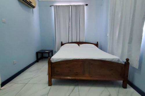 a bedroom with a bed and a window with white curtains at 28 Steber in Roseau
