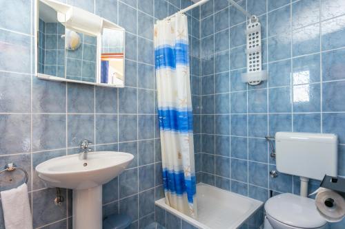 a blue tiled bathroom with a sink and a toilet at Studio Podaca 6736b in Podaca