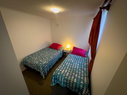 Zimmer mit 2 Betten und einer Lampe an der Wand in der Unterkunft Departamento céntrico con estacionamiento in Concepción