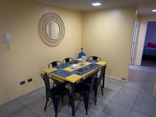 a dining room table with black chairs and a mirror at Departamento céntrico con estacionamiento in Concepción