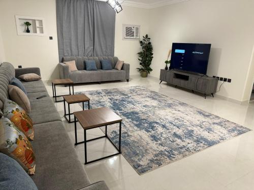 Almadina Apartemetns في المدينة المنورة: غرفة معيشة مع أريكة وتلفزيون بشاشة مسطحة