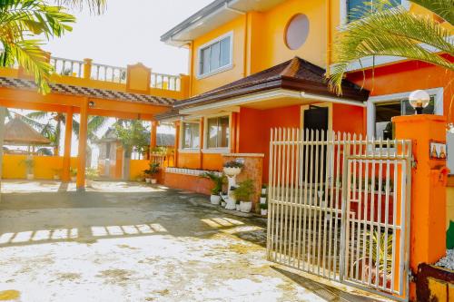 a orange house with a gate in front of it at Simala Beach House Beachfront 4BR Retreat by the Sea in Sibonga