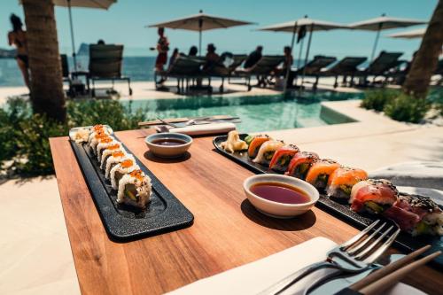 tres platos de comida en una mesa de madera junto a una piscina en ABBY TOURISM en Playa Blanca