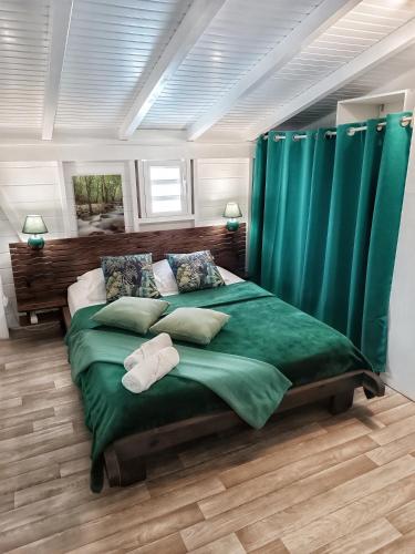 a bedroom with a large green bed with two pillows at Bungalow Bois Détente in Capesterre-Belle-Eau