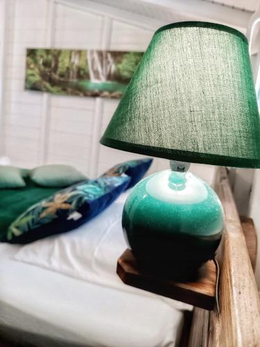 a green lamp sitting on a table next to a bed at Bungalow Bois Détente in Capesterre-Belle-Eau