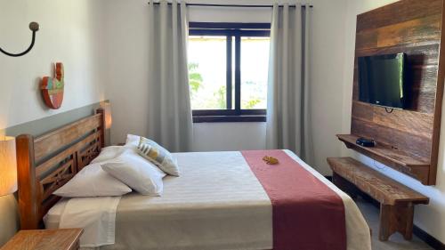 a bedroom with a bed with a tv and a window at Pousada Sete Quedas in Carrancas